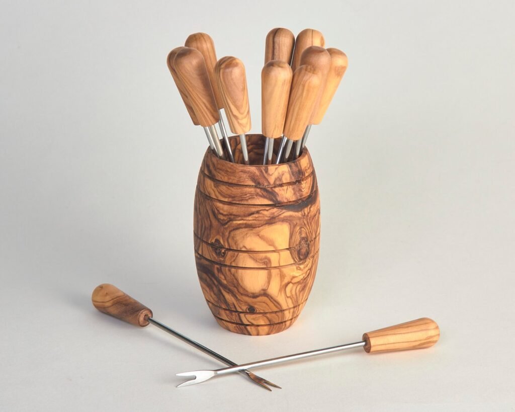 Piques à manche en bois d’olivier et pointes en inox, présentés dans un support en forme de tonneau en bois d’olivier.